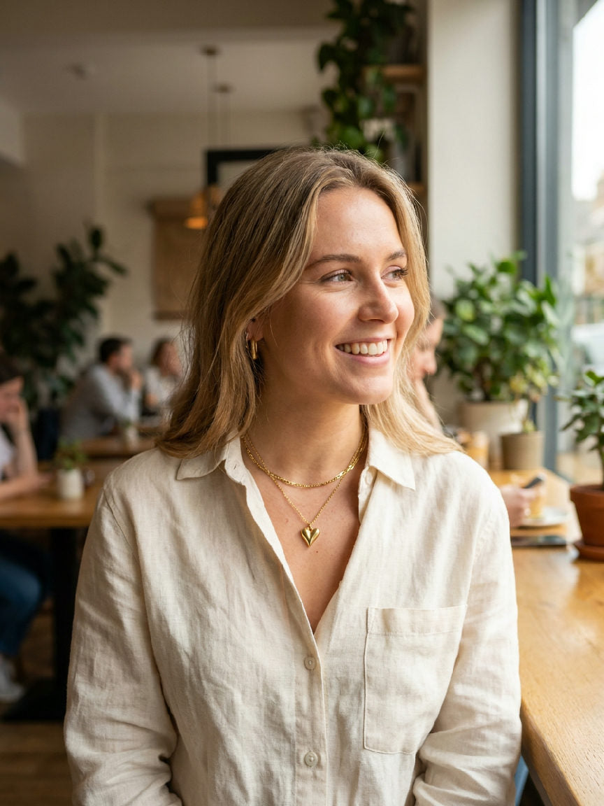 Gouden liefdesketting van roestvrij staal, elegant gedragen door een model, accentueert de decolleté subtiel.