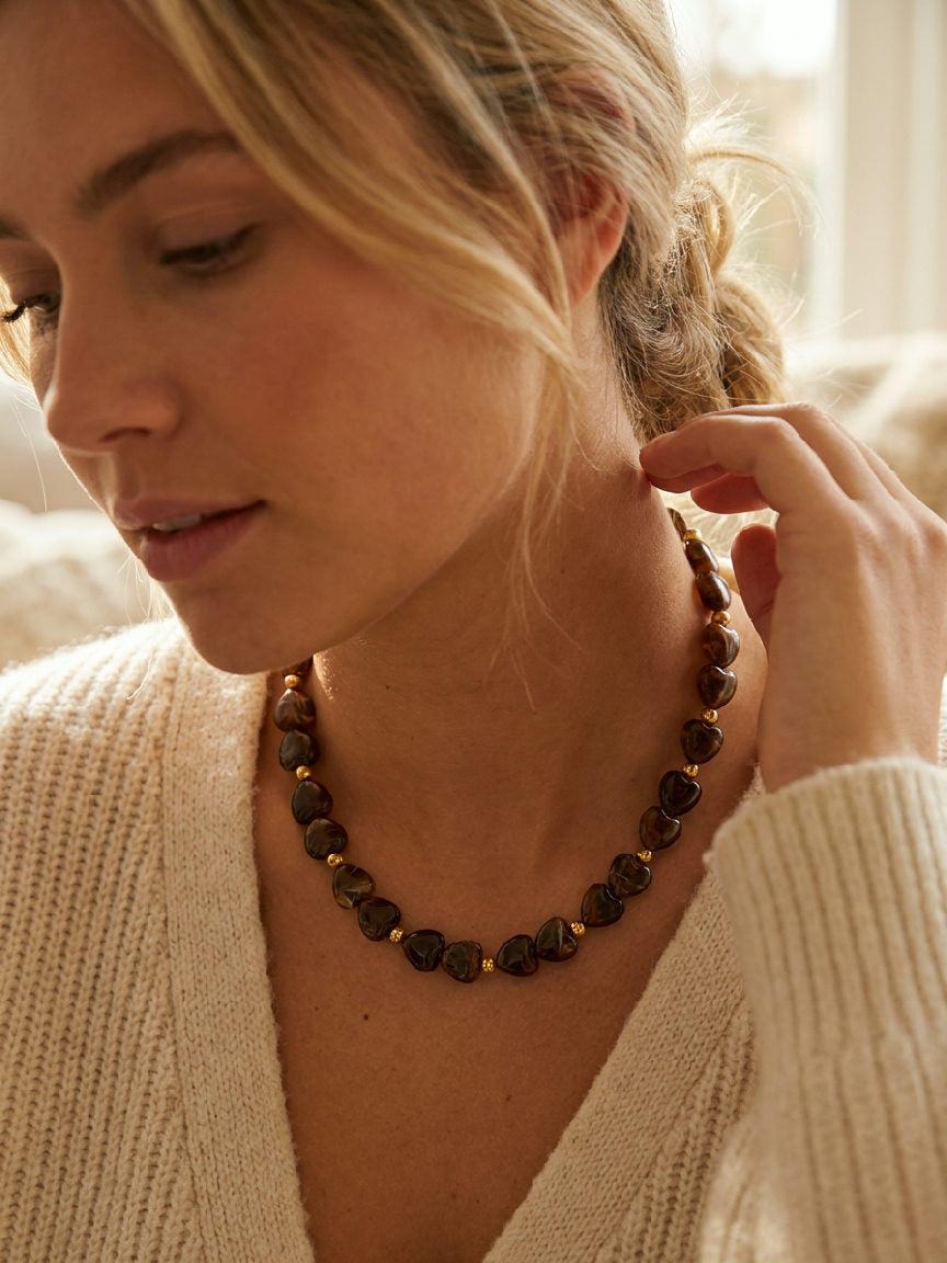 Close-up van een jonge vrouw die een elegante Mila ketting draagt, gemaakt van acryl kralen en roestvrij staal, om haar nek.