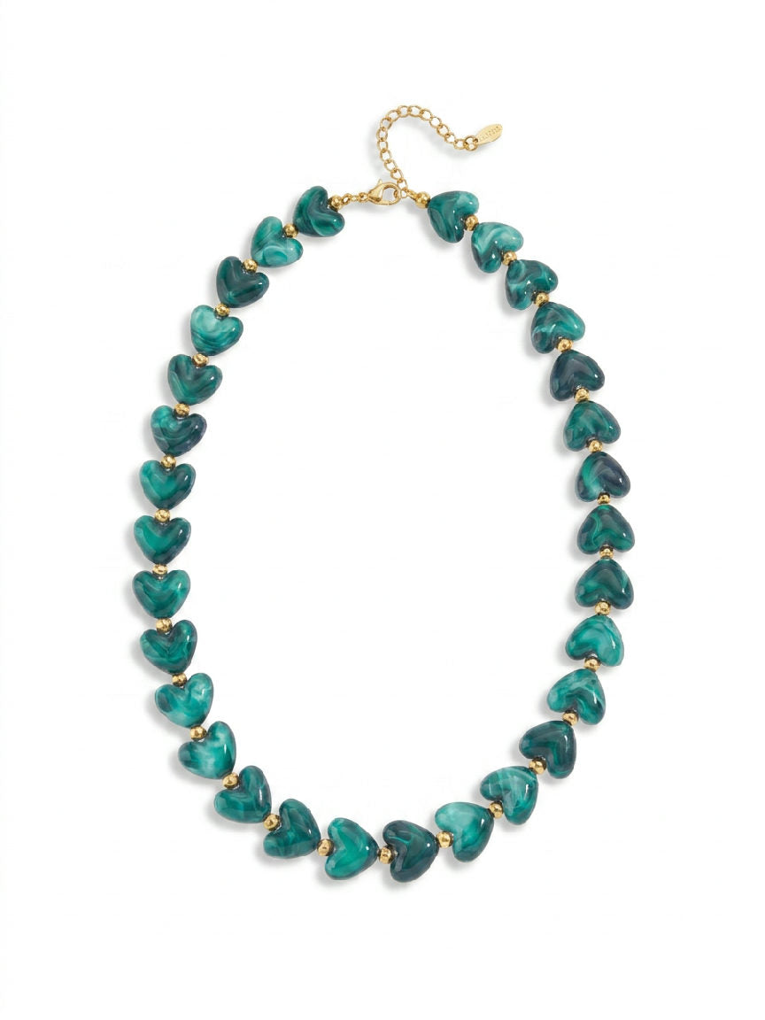 Close-up van een glanzende groene hartjesketting, roestvrij staal, met een fijne ketting en een stralende afwerking
