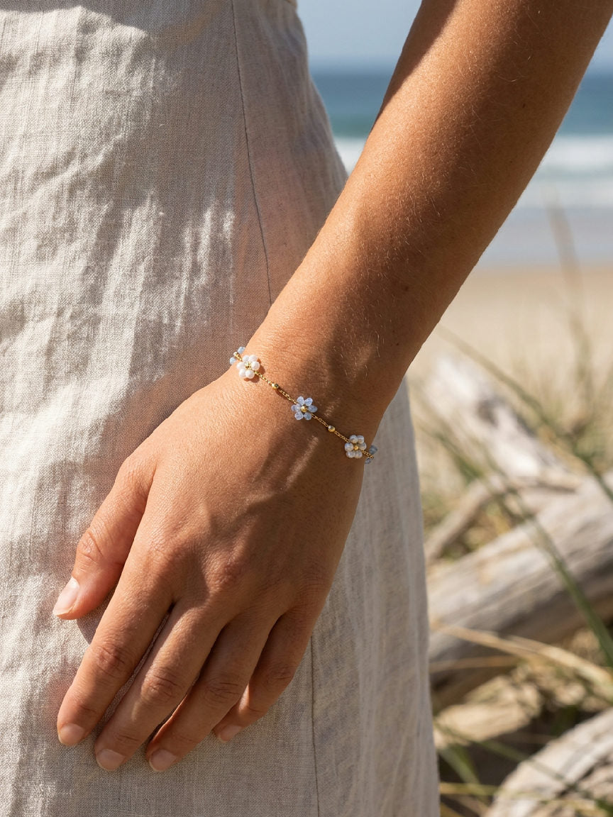 Close-up van een armband van roestvrij staal in lichtblauw, gedragen door een model in een zomerse setting