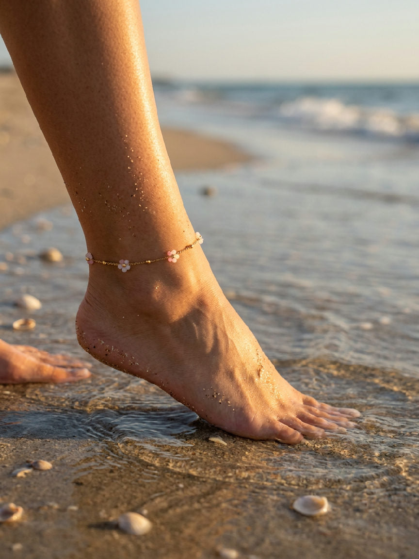 Elegante Miranda enkelband van roestvrij staal in roze kleur, gedragen door een model op een zonnig strand