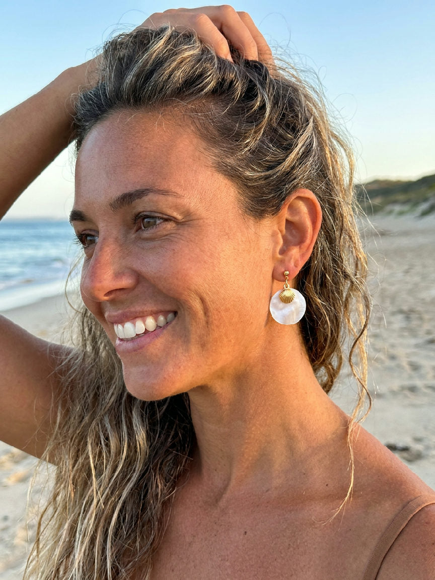 Elegant model draagt zilverkleurige Coastal Shell Drops oorbellen die zachtjes bungelen aan haar oren