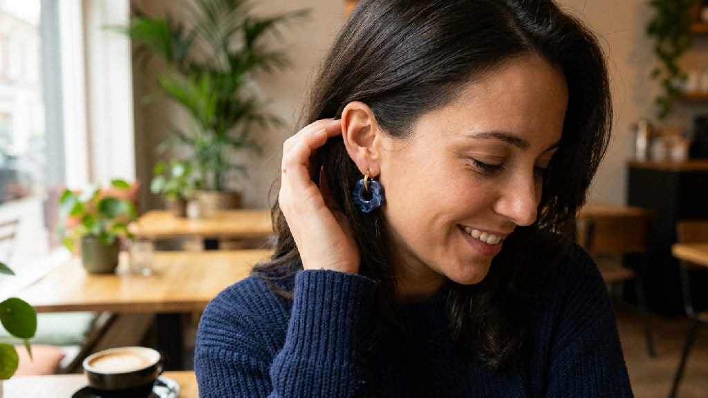 Rosy oorbellen in navy blauw, gedragen aan het oor van een vrouw, subtiel en elegant ontwerp