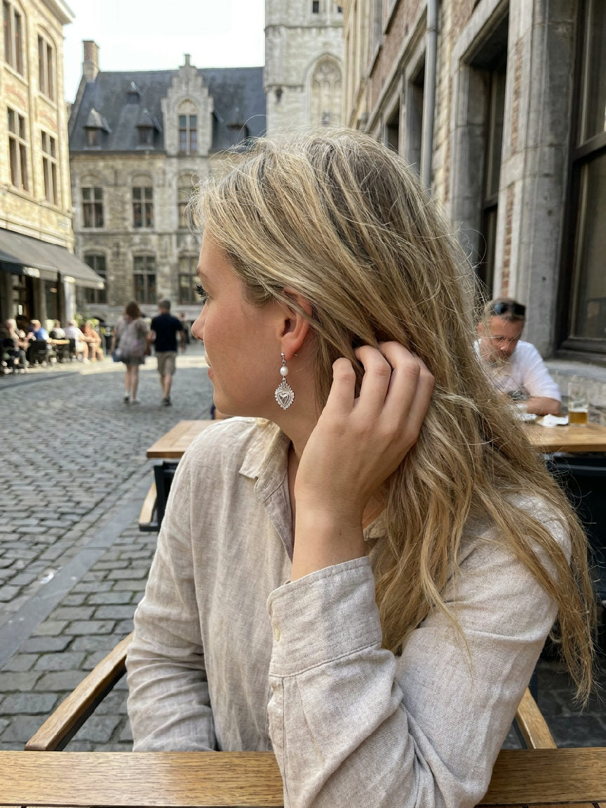 Elegante zilveren hartvormige oorbellen van stainless steel, gedragen door een model, perfect voor een stijlvolle outfit
