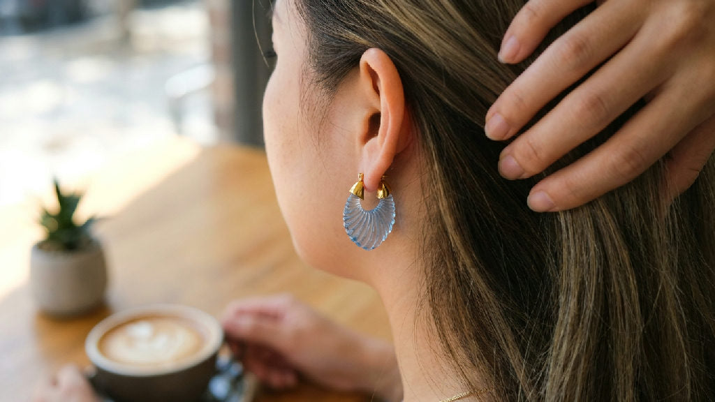 Close-up of blue stainless steel Tamara earrings, showcasing their elegant design and reflective surface when worn.