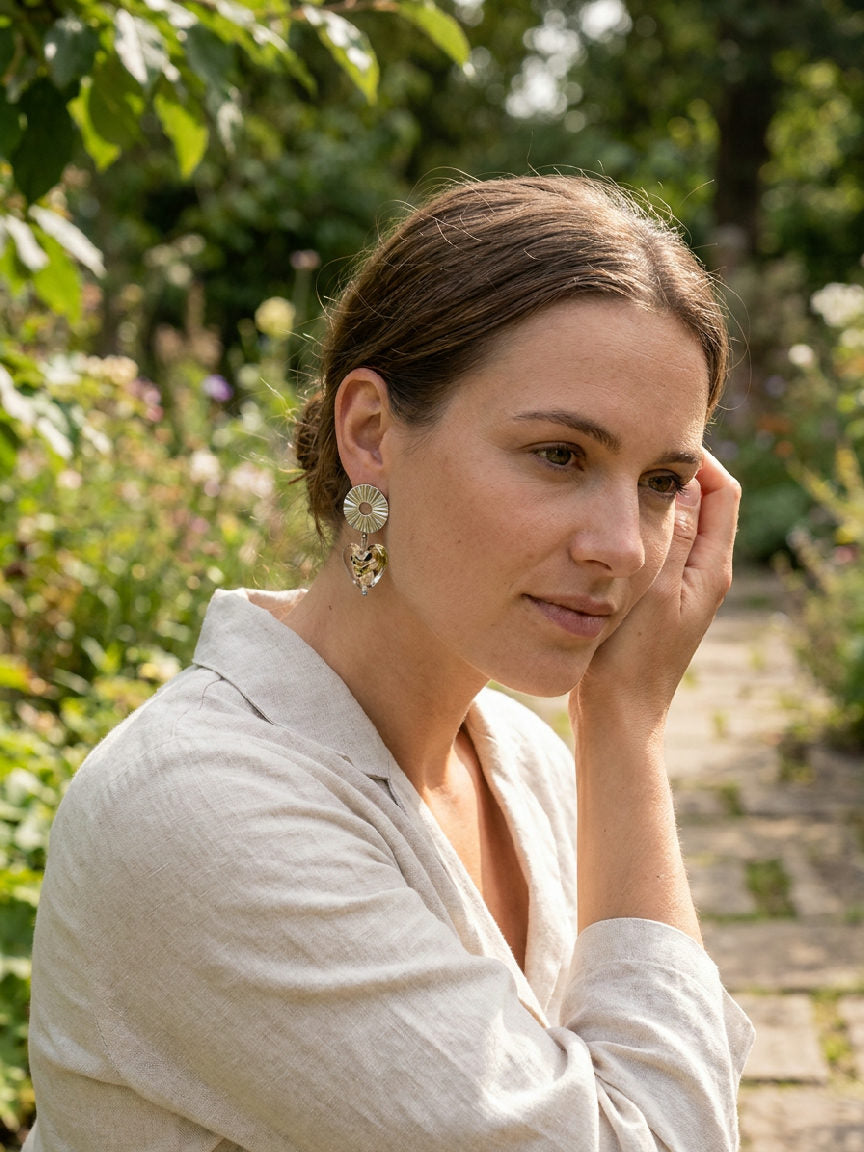Vrouw draagt glazen hartvormige oorbellen van roestvrij staal, haar lachende gezicht duidelijk zichtbaar.
