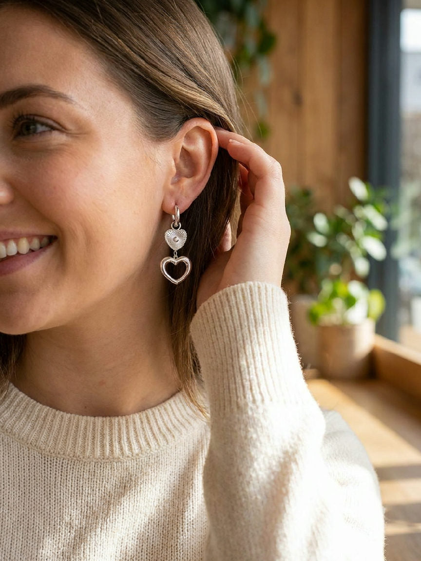 Close-up van een vrouw die elegant zilveren hartslag oorbellen van roestvrij staal draagt, passend bij haar outfit