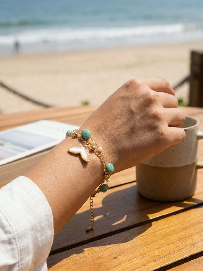 Close-up van een ingewikkelde zilveren roestvrijstalen armband met een walvisstaartontwerp, gedragen door een persoon